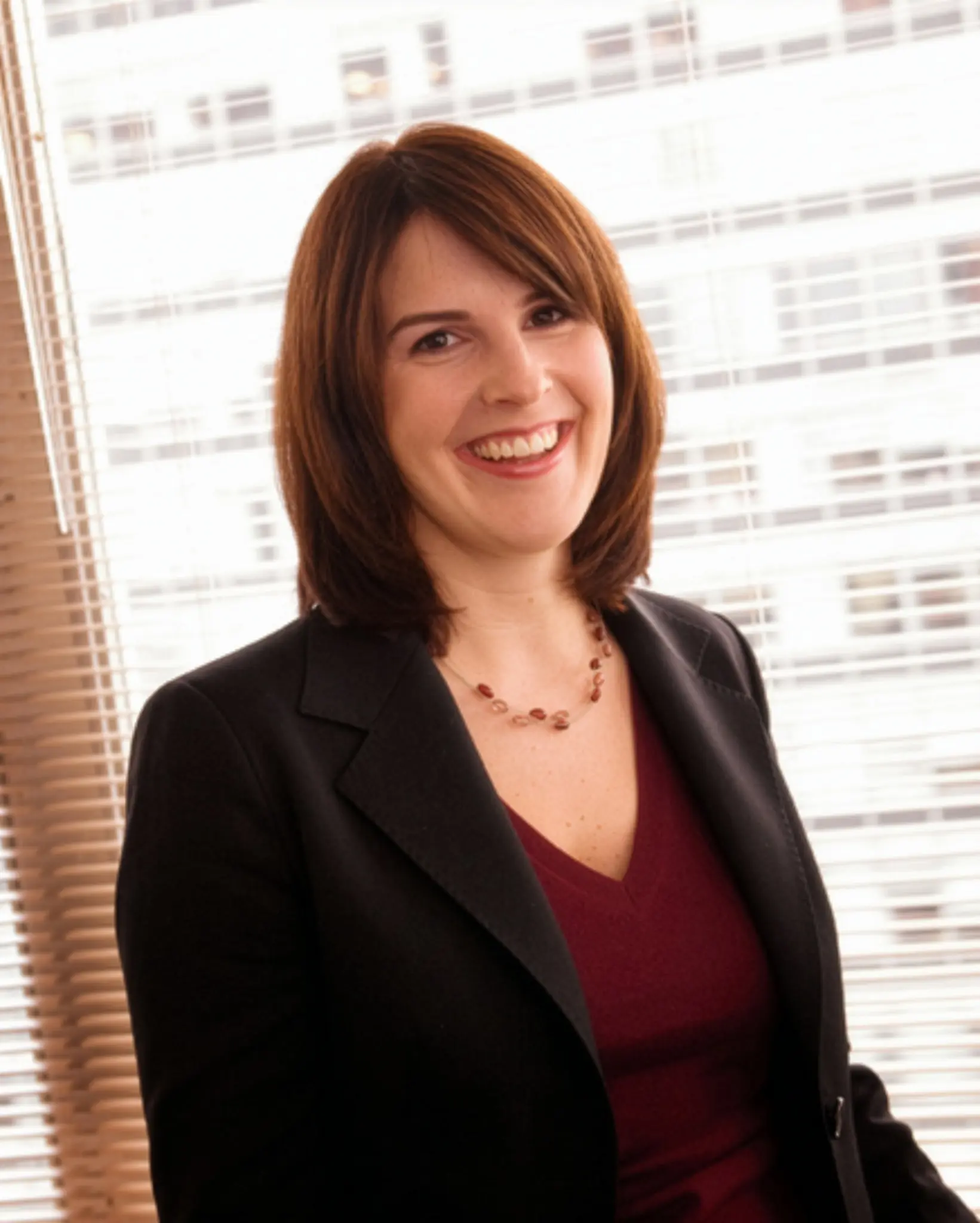 Woman in business attire in front of bright windows