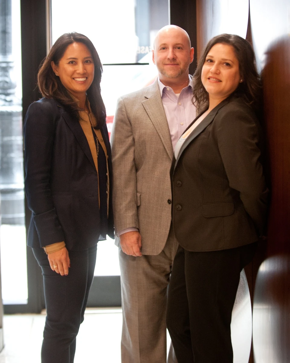 Three people standing together in a bright office