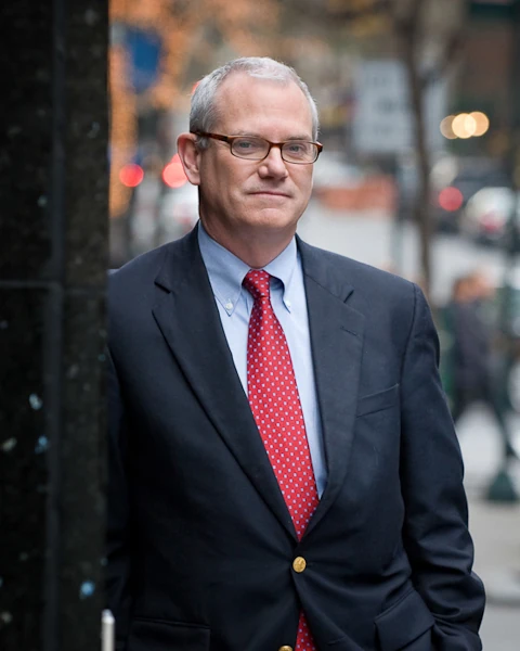 Portrait of a man in a dark suit against a softly blurred New York street